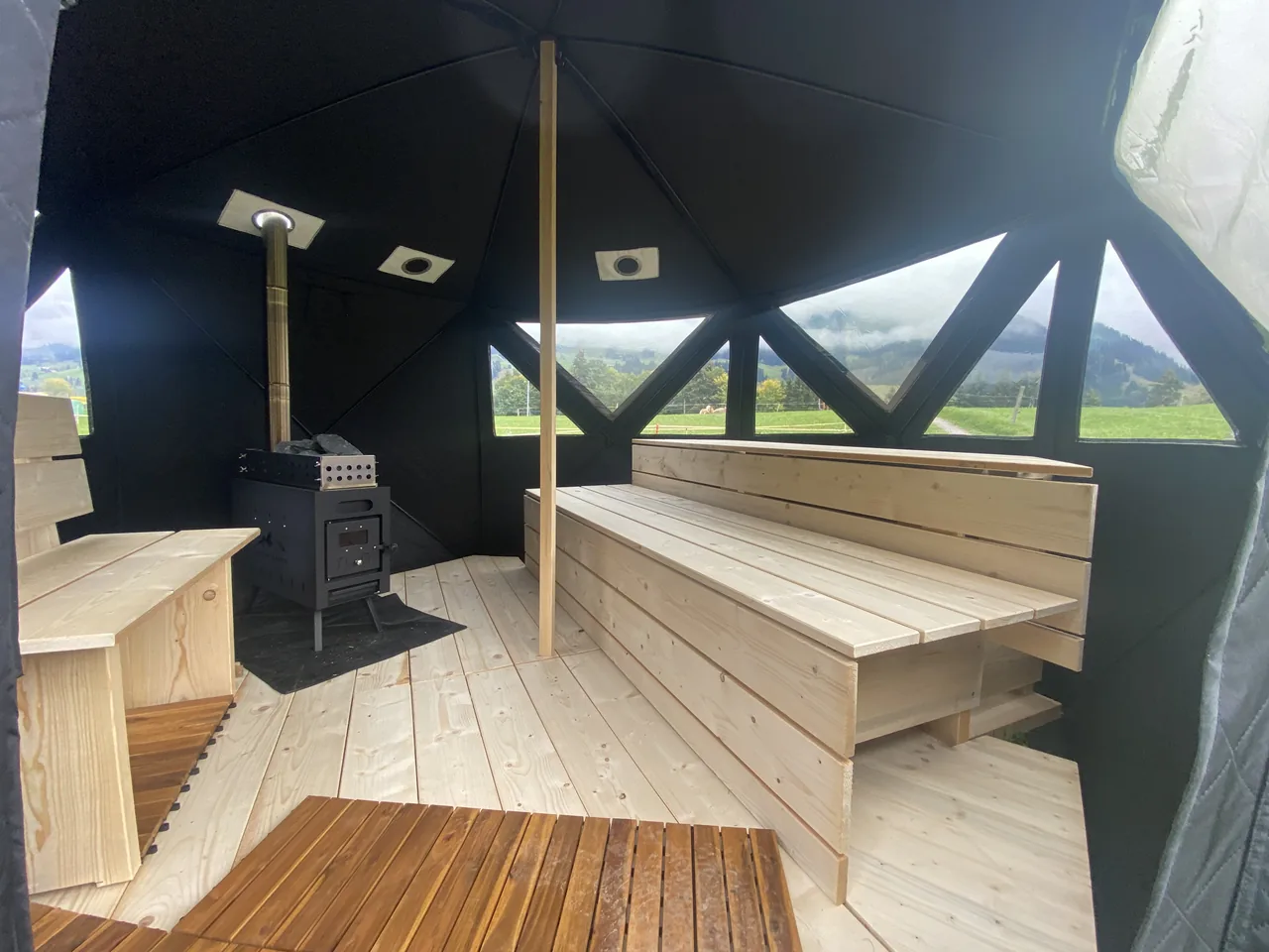 Blick in die Sauna mit Ofen, Bänken und Fenstern