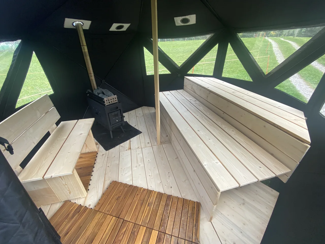Blick in die Sauna mit Ofen und zweistöckiger Bank